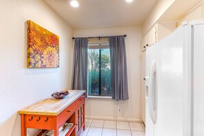 Compact kitchen area with a refrigerator, window, and table.