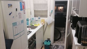 Una cocina compacta con refrigerador, estufa, pileta y un ventanal.