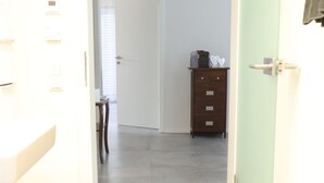 A hallway with a light green door, a white wall, and a wooden dresser with drawers. - die Fewo im Herzen der Pfalz (Lug)