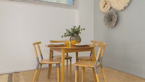 Un comedor con una mesa redonda de madera, seis sillas y un florero con plantas.