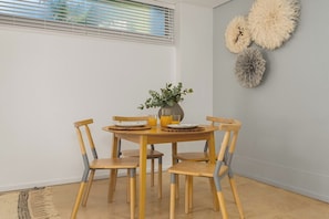 A dining area with a round wooden table, six chairs, and a vase with greenery.