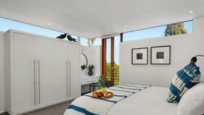 Un dormitorio moderno con una cama grande, un armario y una ventana con vistas a árboles.