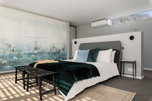 Un dormitorio moderno con una cama grande, aire acondicionado de pared y un ventanal con luz natural.