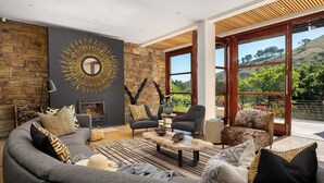 Una sala de estar moderna con chimenea, asientos cómodos y un amplio ventanal con vistas al exterior.