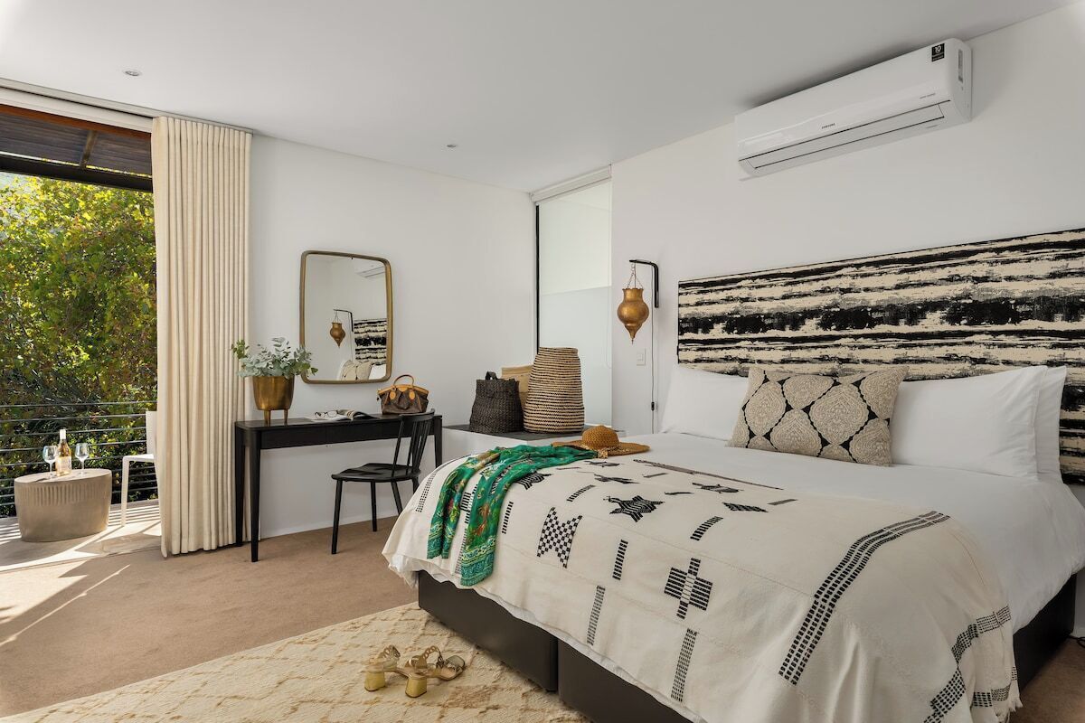 A bedroom with a bed, a desk, a chair, and a large window.