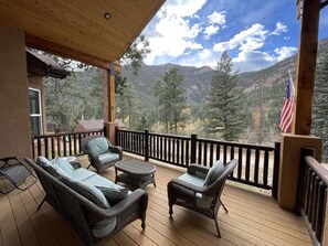 A covered deck with wicker furniture and a view of a mountainous landscape. - Perfect Pike's peak basecamp location & spacious luxury for active family/group (Cascade-Chipita Park)