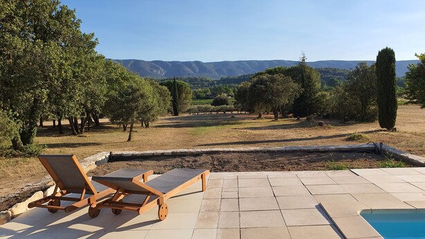 A pool area with lounge chairs and a view of the countryside.