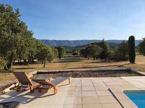 Zona de piscina con sillones de descanso y vistas al campo.