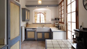 A kitchen with a sink, cabinets, a coffee machine, and a window with curtains.