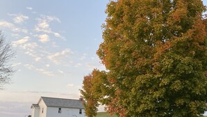 A white house with a sloped roof in a grassy field.