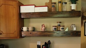 A kitchen with wooden cabinets, a white stove, and various kitchen items on shelves.
