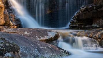 Ein Wasserfall stürzt über Felsen, mit freier Sicht auf den Wasserlauf.