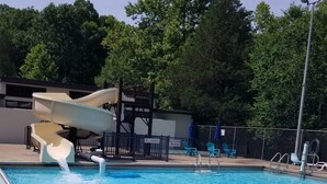 A swimming pool with a water slide, a no running sign, and a no diving sign.