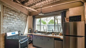 A kitchen with a stove, sink, refrigerator, and window. - Spacious & unique railyard loft w/panoramic balcony views (Santa Fe)
