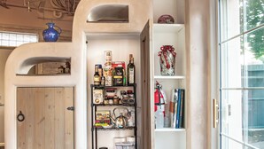 A room with a wooden door, a shelf with various items, a window, and a blue rug. - Spacious & unique railyard loft w/panoramic balcony views (Santa Fe)