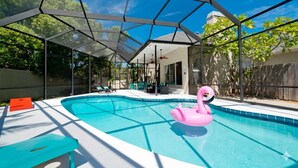 Ein Swimmingpool mit Glasumrandung, einem Flamingo-Schwimmpfiff und einer überdachten Terrasse.