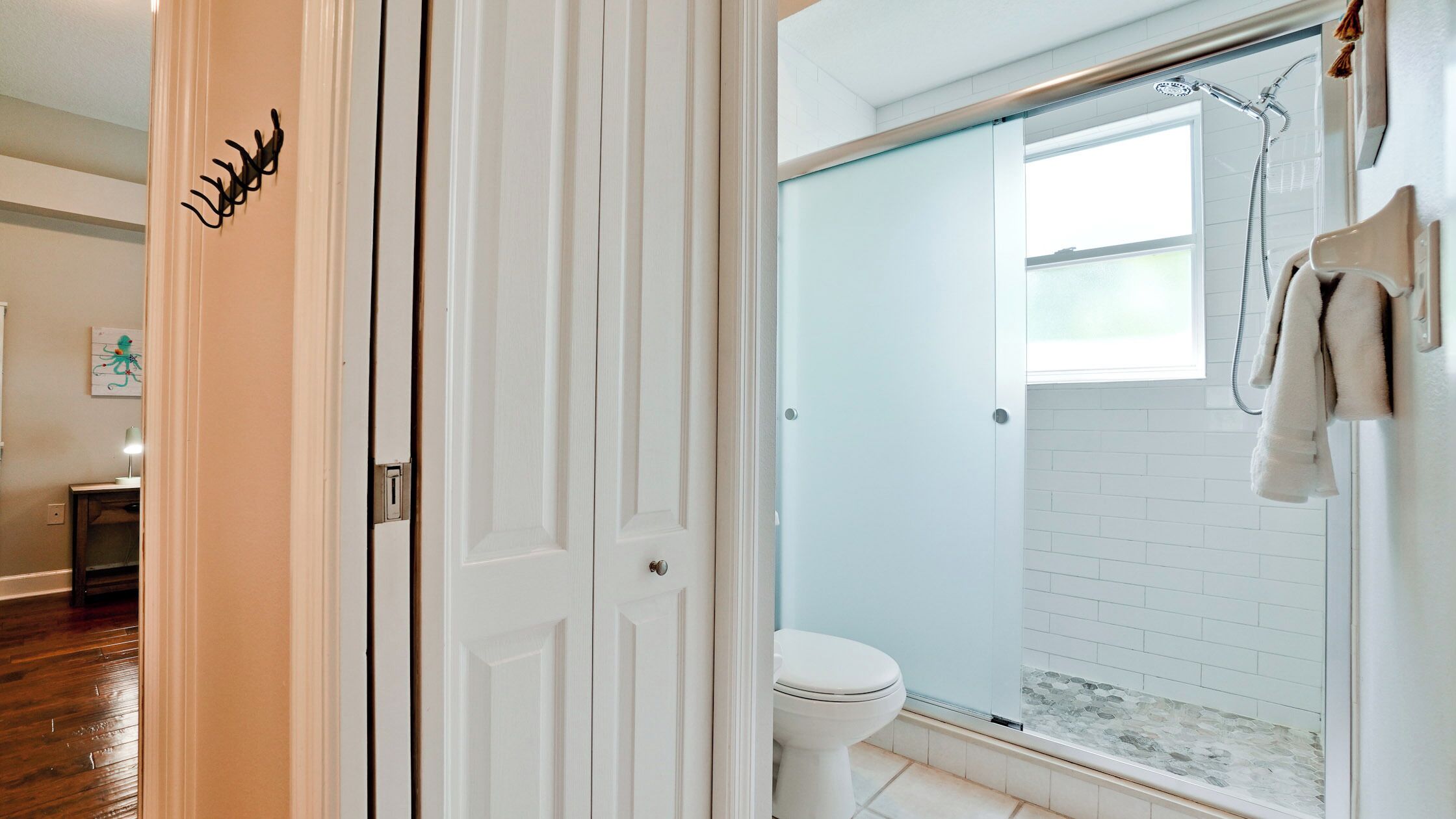 Un baño con cabina de ducha de vidrio, inodoro blanco y una toalla colgada en la pared.