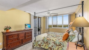 Een slaapkamer met een bed, een dressoir, een televisie en een balkon met uitzicht.