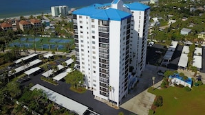 Een hoog hotel met een blauw dak, meerdere verdiepingen en een parkeerplaats ervoor.