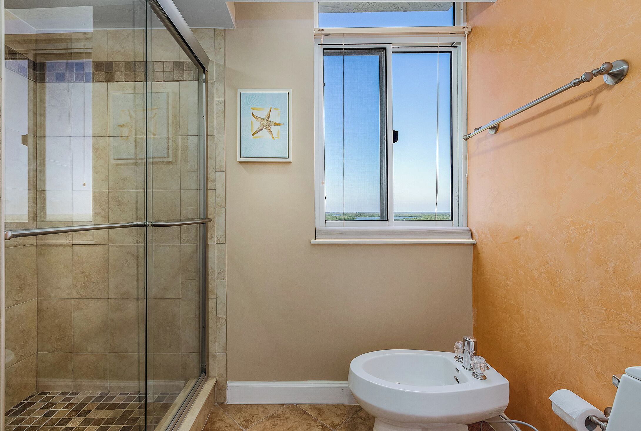 Une salle de bain avec une douche à parois de verre, un lavabo et une fenêtre.