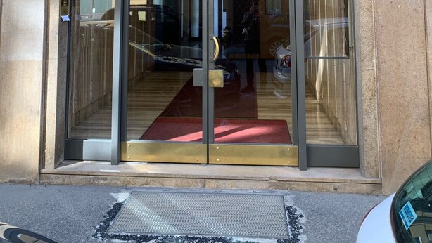 Une entrée d’immeuble avec une porte en verre, un tapis rouge et un panneau portant le numéro 11 sur le mur.