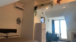 Une chambre avec un lit, un réfrigérateur, un bureau avec une chaise et une fenêtre.