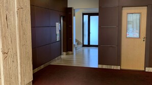 Un couloir avec un mur d’accent en bois, un sol recouvert de moquette et une porte dotée d’une fenêtre en verre dépoli.