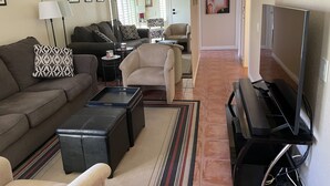 Una sala de estar con sofá, sillones, una mesa de centro, televisor y chimenea.