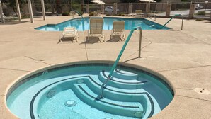 Una piscina con un diseño espiral único, rodeada de sillones de descanso y una zona delimitada por una valla.