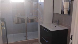A modern bathroom with a glass shower enclosure, a vanity with a mirror, and a toilet. - Large F3 apartment with balcony (Pierrelaye)