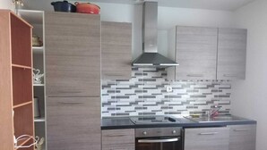 A modern kitchen with grey cabinetry, a tiled backsplash, and a built-in oven. - Large F3 apartment with balcony (Pierrelaye)