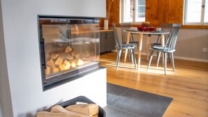 A modern kitchen with a built-in fireplace, wooden cabinets, and a dining area with chairs and a table.