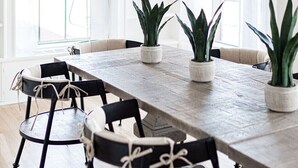 Un comedor moderno con una mesa de madera, sillas negras y plantas en macetas.