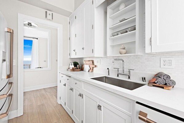 Una cocina moderna con armarios blancos, un lavamanos doble y vistas al exterior.