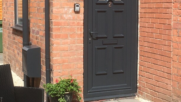 A black door with a number 2, a brick wall, a black outdoor light, and a small potted plant. - One Bedroom Maisonette with Terrace, Kidderminster (Kidderminster)