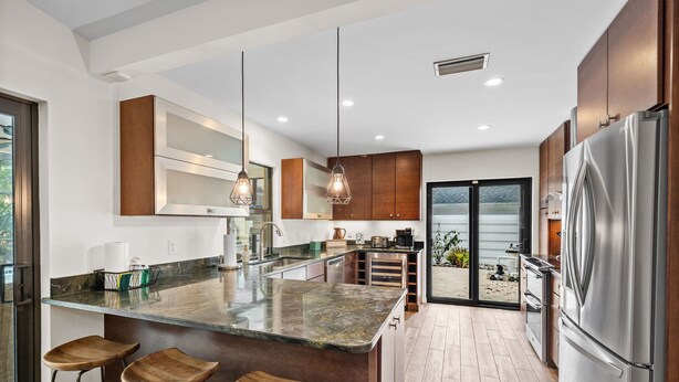 Una cocina moderna con una isla grande, taburetes de bar, electrodomésticos de acero inoxidable y vistas al exterior.