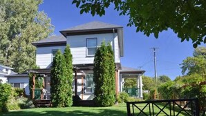 Une maison à deux étages avec un porche à l’avant, un patio couvert et une pelouse bien entretenue.