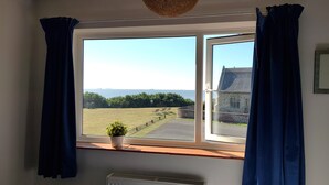 A window with a view of a grassy field and a building across the street. - Sea View House: Large modern Beachfront home with downstairs Bedroom & Bathroom (Lowestoft)