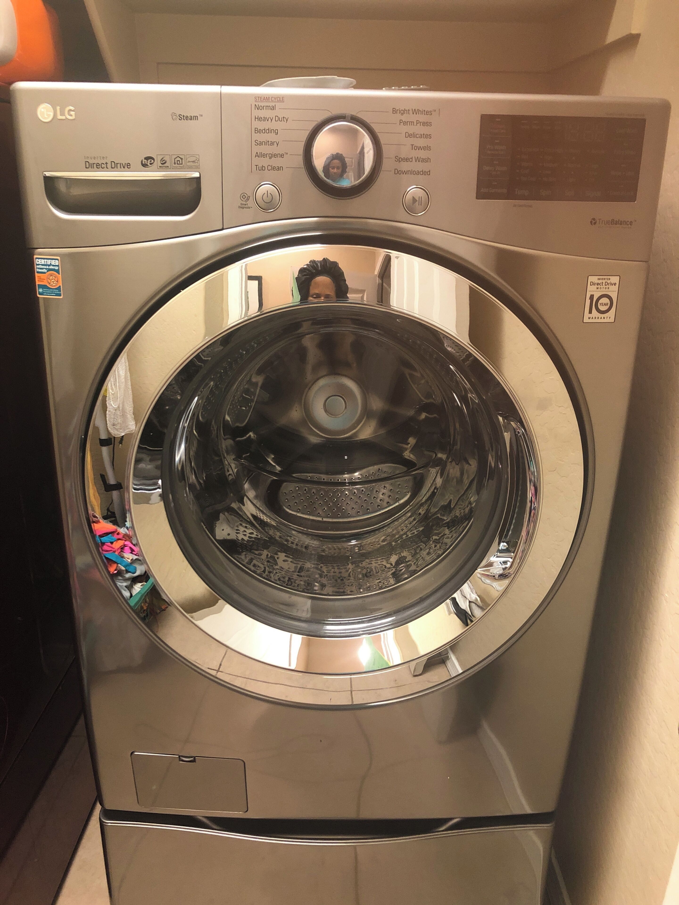 Lavadora LG Direct Drive de carga frontal con acabado de acero inoxidable, un panel de control con diversas opciones de ciclo y una etiqueta que indica una garantía de 10 años.
