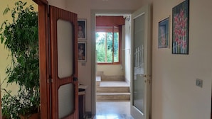 A hallway with a wooden door, a potted plant, and a staircase leading to a balcony. - "Da Celeste" Very bright apartment in a single house surrounded by greenery (Montegaldella)