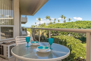 Enjoy a serene view of the lush landscape from this balcony, featuring a table for outdoor dining.