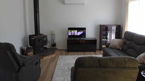 A living room with a fireplace, a television, and seating. - Paradise Retreat (Paradise Beach)