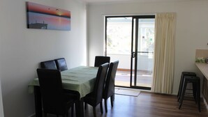 A dining area with a table and chairs, a painting on the wall, and a sliding glass door leading to an outdoor area. - Paradise Retreat (Paradise Beach)