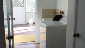 A laundry room with a washing machine, a drying rack, and a door leading to a balcony. - Paradise Retreat (Paradise Beach)