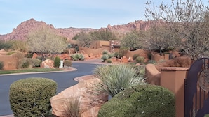 Una zona residenziale con una strada sinuosa, giardini curati e montagne sullo sfondo.