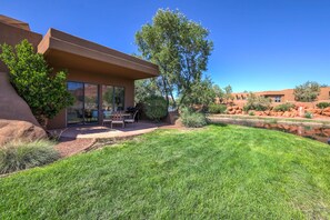A modern house with a patio, a small pool, and a well-maintained lawn.