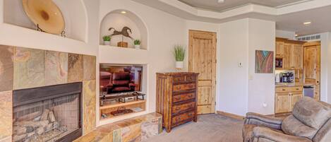 Un salón comedor amplio con chimenea, asientos cómodos y una cocina al fondo.