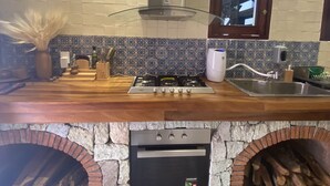 Een keuken met een gasfornuis, een inbouwoven, een roestvrijstalen spoelbak en een decoratieve spatwand.