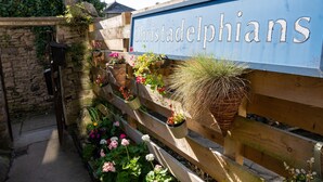 A sign reading "Christadelphians" with a wooden fence and hanging planters with flowers. - 23 Tanners Yard - Modern studio-style apartment in the heart of Kendal (Dog-friendly) (Kendal)