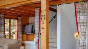 Ett mysigt rum med en soffa, en tv och en trappa.